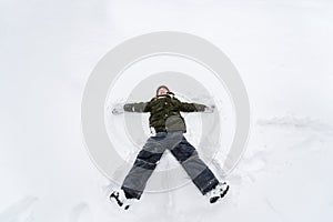 Cute little boy lie on white snow. LIttle boy having fun on winter day