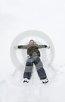 Cute little boy lie on white snow. LIttle boy having fun on winter day