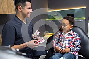 Cute little boy listening to the doctor who shoing him a denture