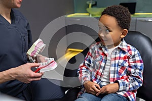 Cute little boy listening to the doctor who shoing him a denture