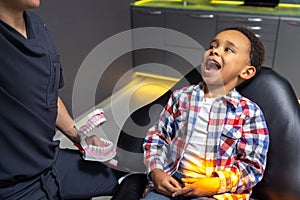 Cute little boy listening to the doctor who shoing him a denture