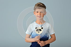 Cute little boy with lollipop on color background