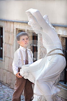 Cute little boy looking at white statue