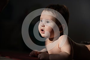 Cute little boy lying on his forearms on the floor.