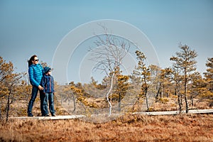 Cute little boy with mother walking on trail in swamp, Kemeri national park, Latvia photo