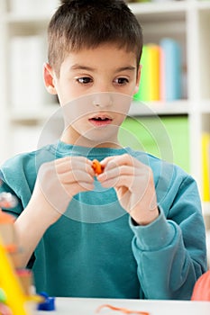 Cute little boy moulds from plasticine on table