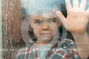 Cute little boy near window. Rainy day