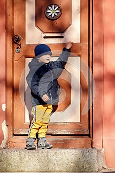 A cute little boy next to a big beautiful vintage door during a fall walk in the old town