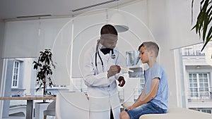 Cute little boy openning his mouth to the young doctor who looking at his throat.