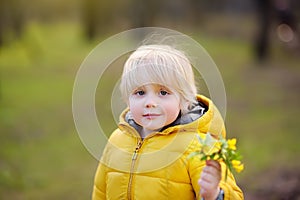 Cute little boy pick wild flowers in park