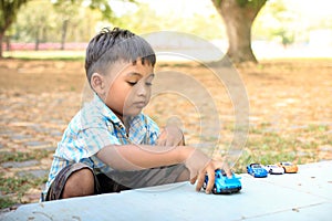 Cute little boy play toy car in the green park