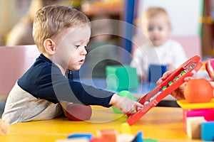 Cute little boy playing with abacus in nursery. Preschooler having fun with educational toy in daycare or kindergarten