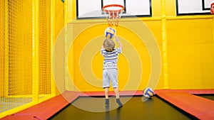 Cute little boy playing in basketball on playground at amusement park