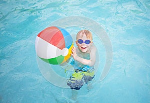 Cute little boy playing with Beach ball in a swimming pool