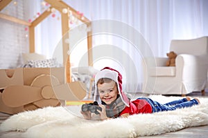 Cute little boy playing with binoculars and cardboard airplane