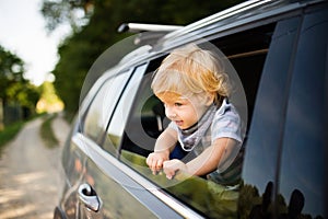 Little boy playing in the car, leaning out of window.