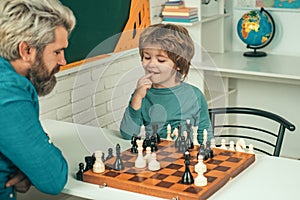 Cute little boy playing chess with father. Handsome teacher giving private lessons chess to preschool boy. Back to