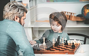 Cute little boy playing chess with Parents. Handsome teacher giving private lessons chess to preschool boy. Educational