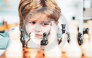 Cute little boy playing chess. Thinking kid. Concentrated boy developing chess strategy, playing board game.