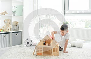 Cute little boy playing with dollhouse