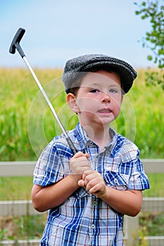 A cute little boy playing golf at home in the back yard.