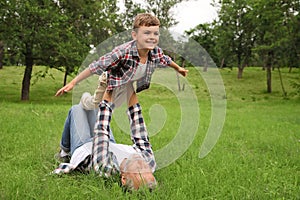 Cute little boy playing with grandfather in park