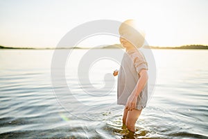Cute little boy playing by a lake or river on hot summer day. Adorable child having fun outdoors during summer vacations
