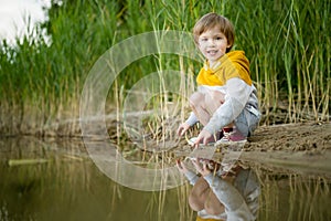 Cute little boy playing by a lake or river on hot summer day. Adorable child having fun outdoors during summer vacations