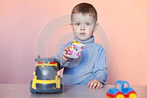 A cute little boy playing with model car collection. Toy mess in child room.