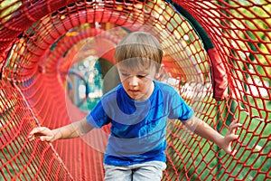 Cute little boy playing outdoors. Child having fun in tunnel at the modern playground. Happy childhood. Summer holidays