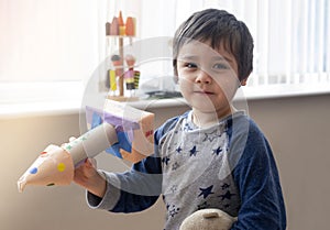 Cute little boy playing with spaceship, Happy child holding toy rocket, Portrait of funny kid, Toddler creativity, Concept for diy