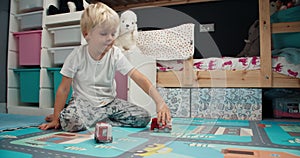 Cute little boy playing with toy firetruck in child bedroom in home