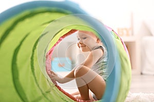 Cute little boy playing with toy tunnel at home