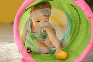 Cute little boy playing with toy tunnel at home