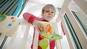 Cute little boy playing toys with his little baby brother lying in crib. Concept of family happiness and baby