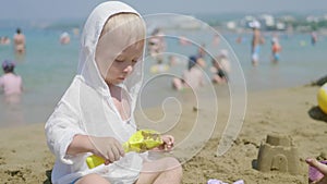 The cute little boy playing toys with sand at sea beach. Child os on vacation in summer at the beach on vacations.