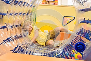 Cute little boy, playing in Zorb a rolling plastic cylinder ring with a hole in the middle, intdoor