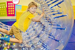 Cute little boy, playing in Zorb a rolling plastic cylinder ring with a hole in the middle, intdoor