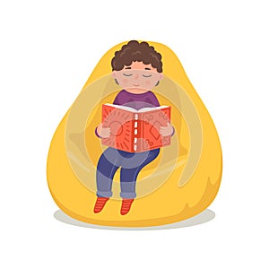 Cute little boy reading book in bean bag