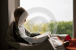 Cute little boy reading book