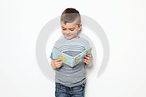 Cute little boy reading book on white