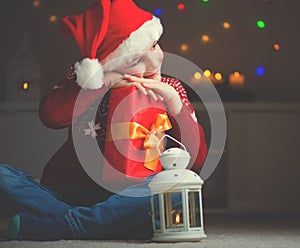 Cute little boy in red hat with gift and  latern waiting Santa Claus