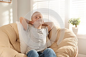 Cute little boy relaxing in papasan chair photo