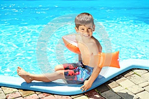 Cute little boy resting near swimming pool