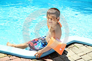 Cute little boy resting near swimming pool