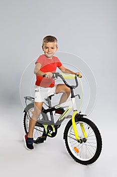 Cute little boy riding bicycle on grey