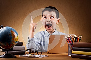 Cute little boy schoolboy doing homework at a table with books