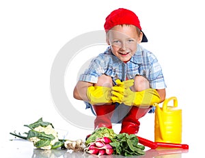 Cute little boy with scoop, fresh organic vegetables and watering can