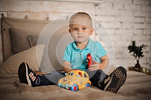 Cute little boy sitting on the bed with a car toy