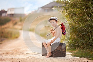 Cute little boy, sitting on a big old suitcase, vintage, holding